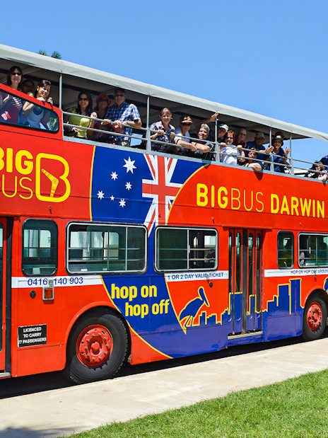 Open-top red bus with tourists on a Darwin city tour.