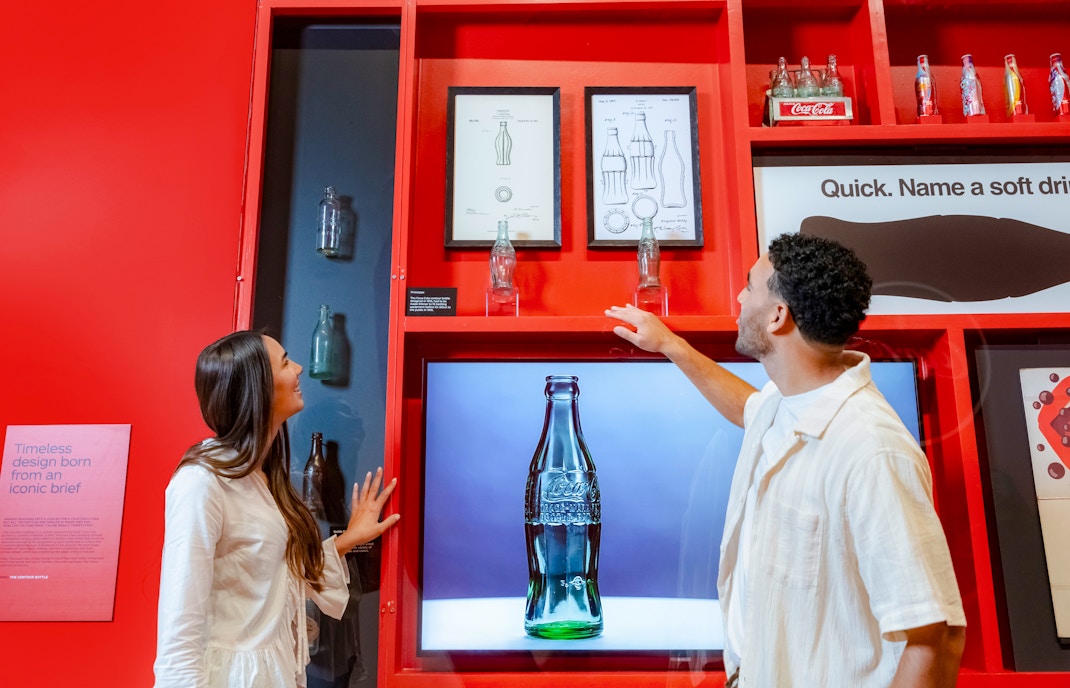 Couple examining Coca-Cola bottle designs at World of Coca-Cola, Atlanta.
