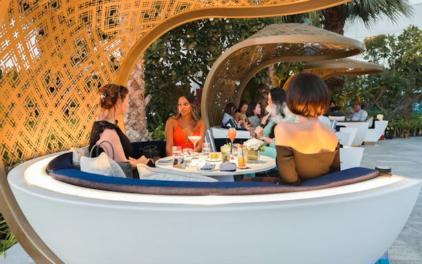 Guests enjoying dining at Uma Lounge, Burj Al Arab, with drinks and conversation.