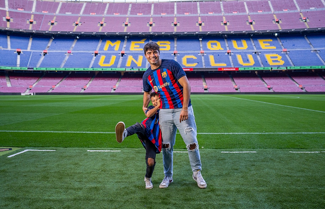 Father and child in FC Barcelona jerseys on Camp Nou field, Barcelona.
