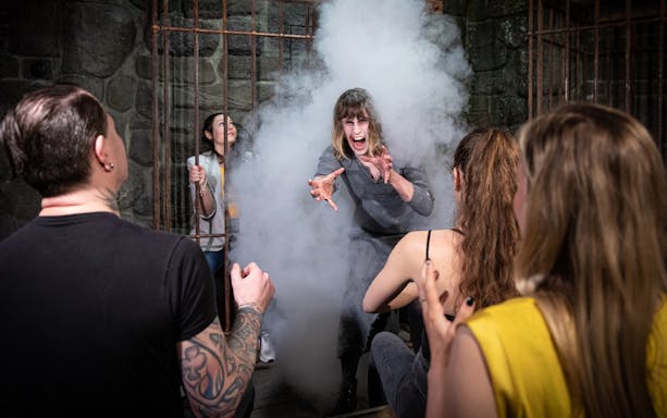 Visitors experience a dramatic scene at Berlin Dungeon with smoke and actors.