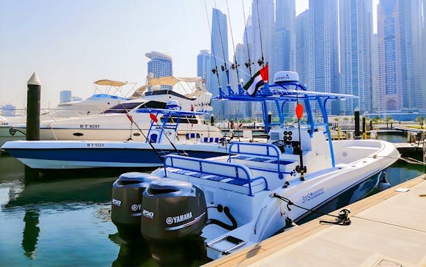 Private fishing charter boat docked in Dubai Marina with city skyline in the background.