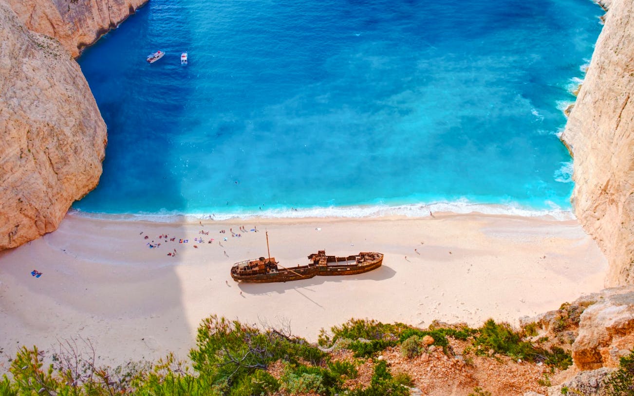 Shipwreck Beach in Zakynthos with shipwreck on sandy shore and turquoise water.