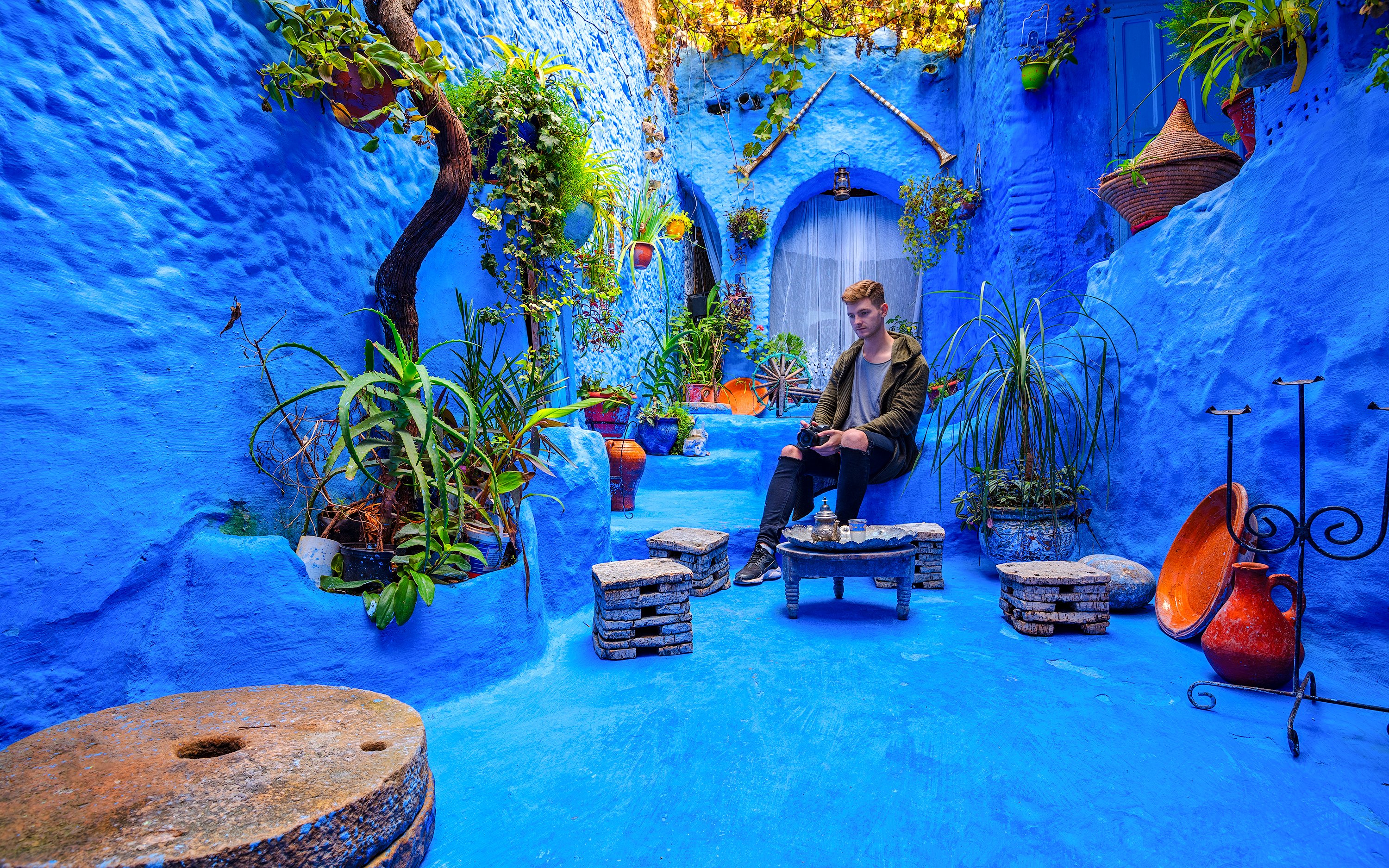 Courtyard with blue walls and plants in the medina of Chefchaouen, Morocco.