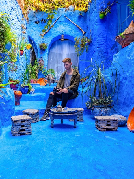 Courtyard with blue walls and plants in the medina of Chefchaouen, Morocco.