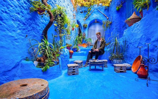 Courtyard with blue walls and plants in the medina of Chefchaouen, Morocco.