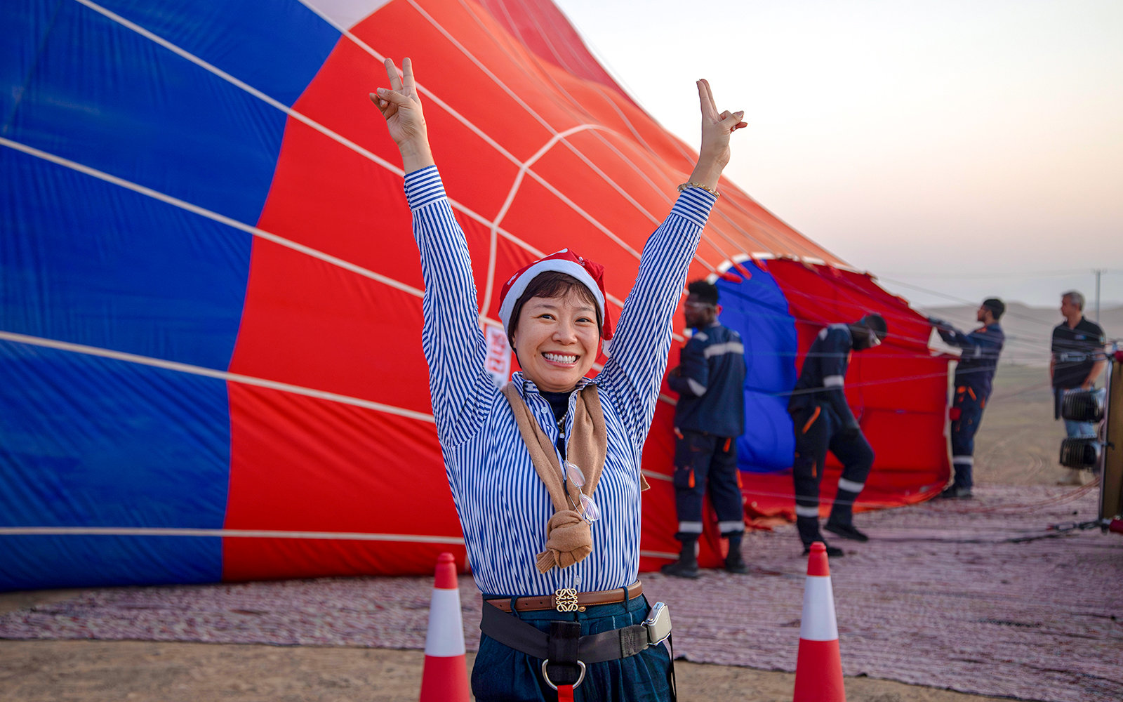 Person celebrating in front of a hot air balloon being prepared in Ras Al Khaimah.