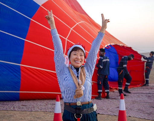 Person celebrating in front of a hot air balloon being prepared in Ras Al Khaimah.