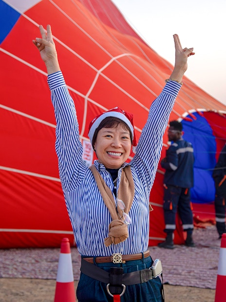 Person celebrating in front of a hot air balloon being prepared in Ras Al Khaimah.