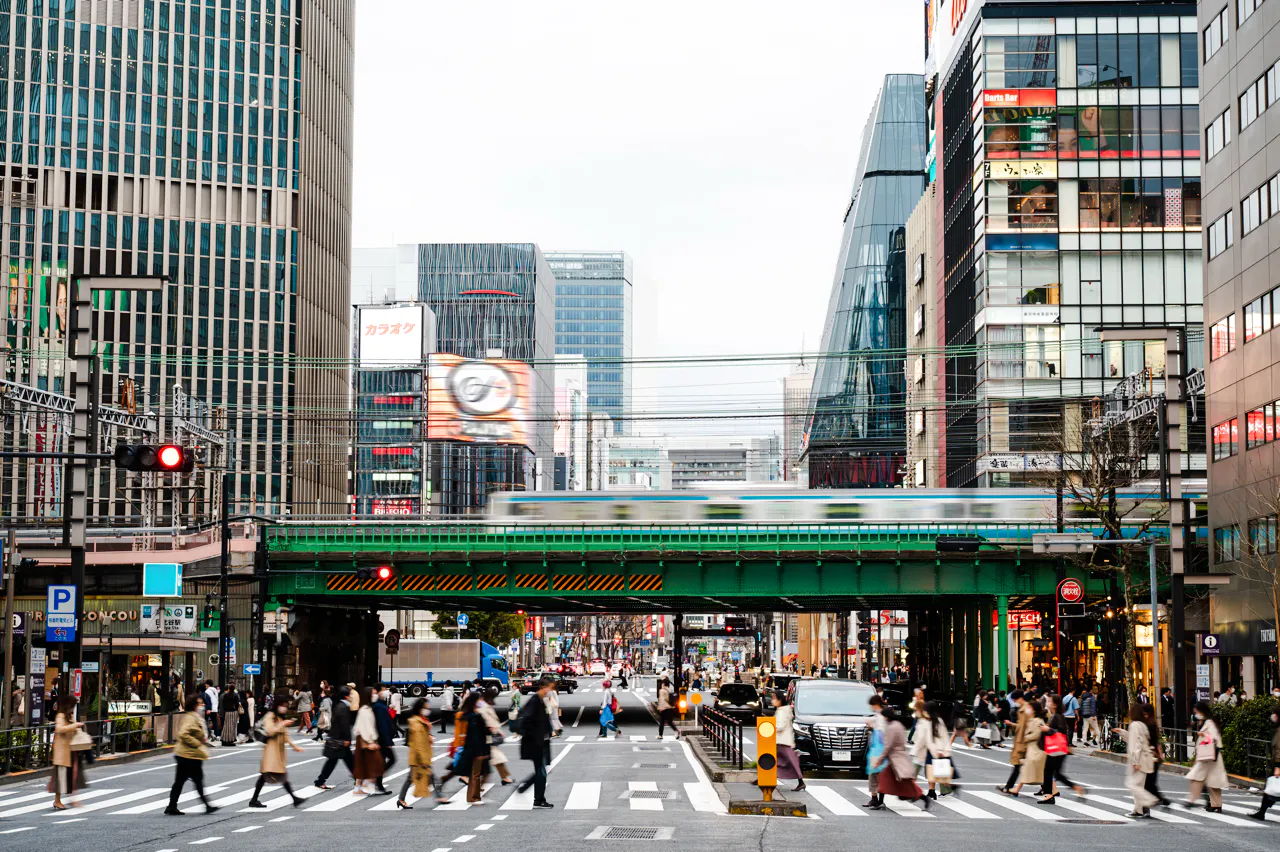 Shibuya street scene with pedestrians and train, Tokyo nightlife hub.