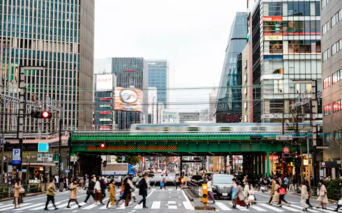 Shibuya street scene with pedestrians and train, Tokyo nightlife hub.