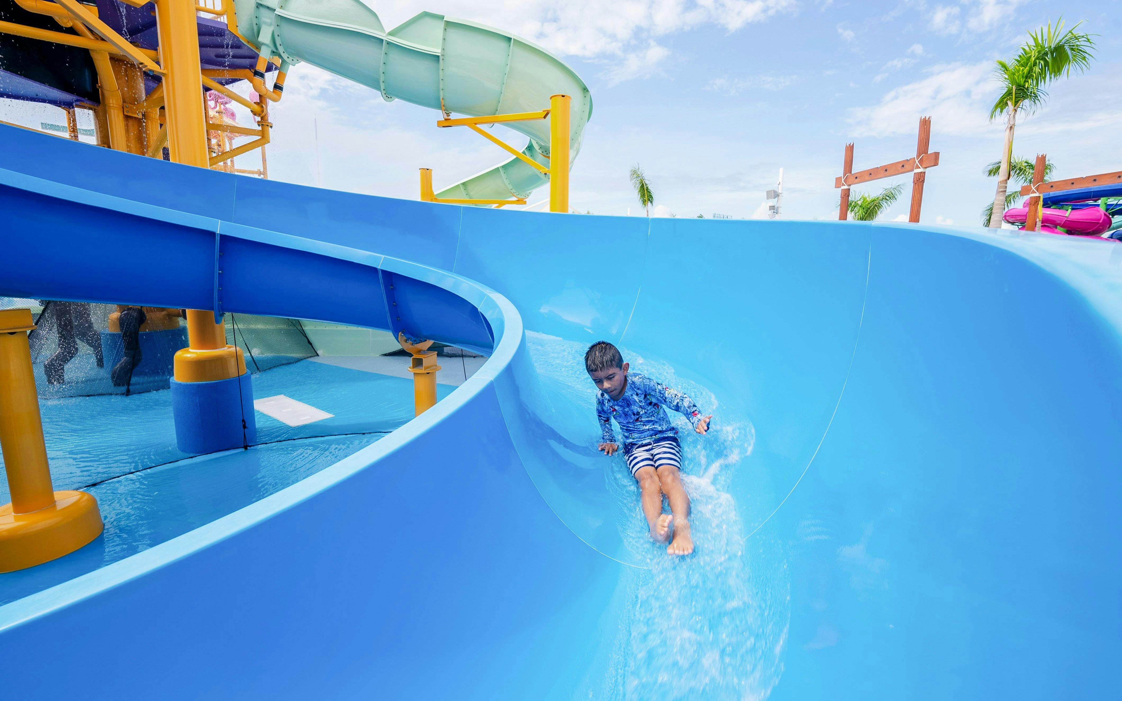 Child sliding down blue water slide at Splash Island, Hurricane Harbor Arlington.