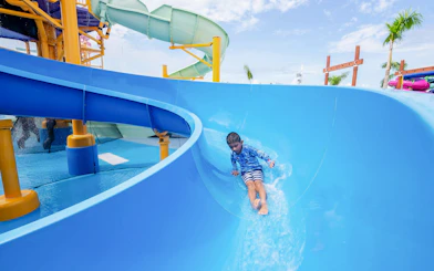 Child sliding down blue water slide at Splash Island, Hurricane Harbor Arlington.