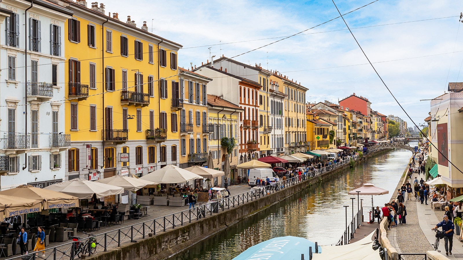 Milan canal with boats and historic buildings in the background.