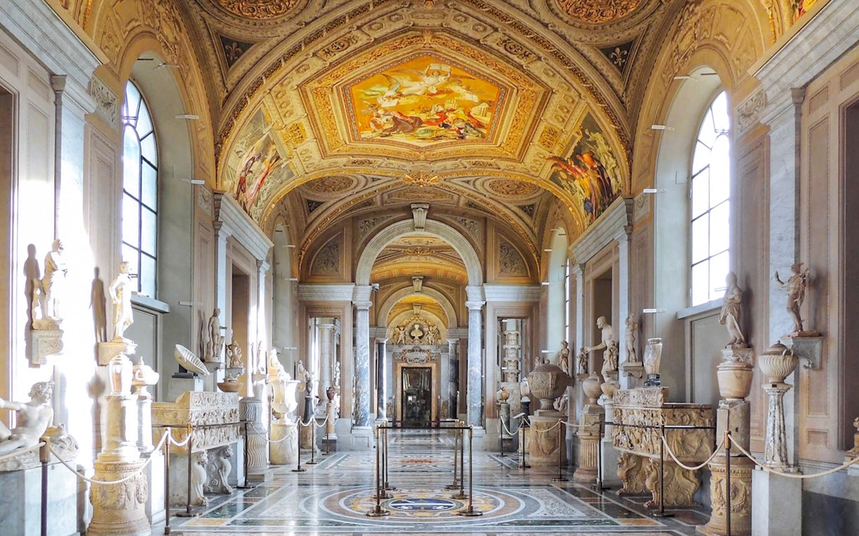 Gallery of the Candelabra in Vatican Museum with sculptures and ornate ceiling.