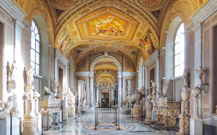 Gallery of the Candelabra in Vatican Museum with sculptures and ornate ceiling.