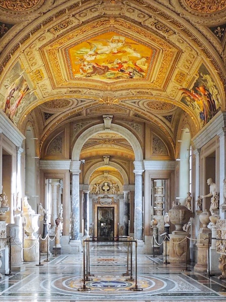 Gallery of the Candelabra in Vatican Museum with sculptures and ornate ceiling.