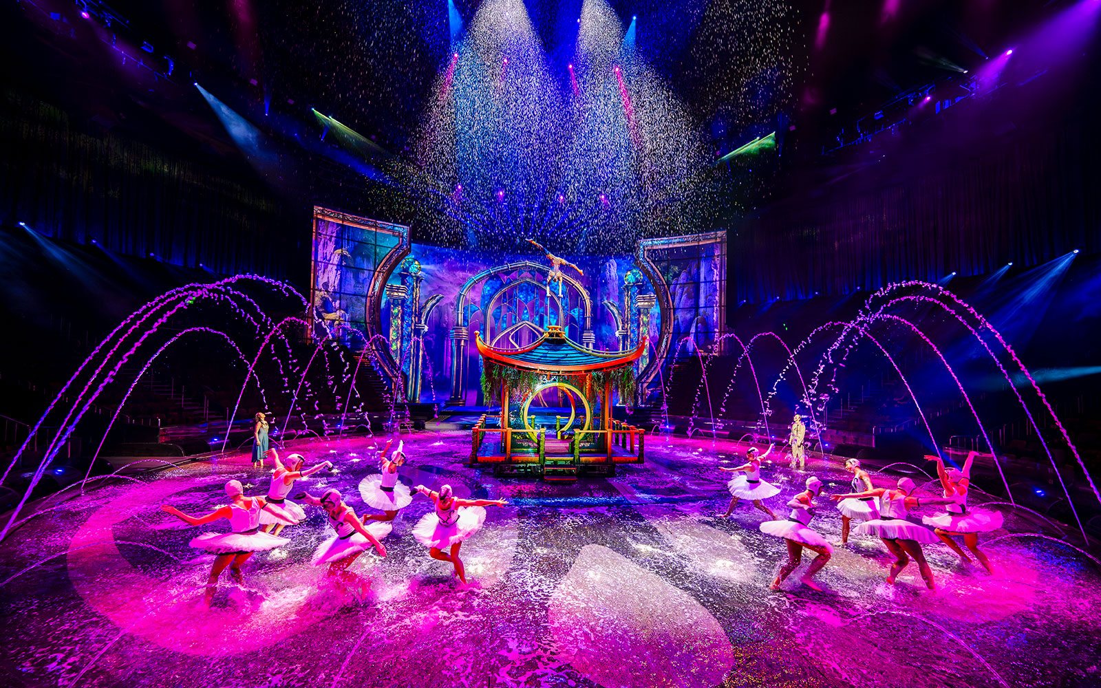 Performers in water dance at House of Dancing Water show, vibrant stage with fountains.