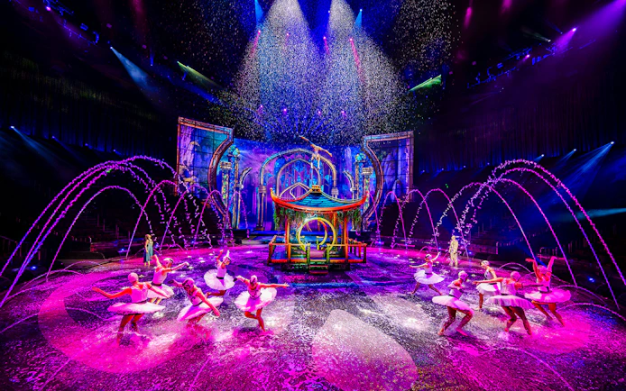 Performers in water dance at House of Dancing Water show, vibrant stage with fountains.