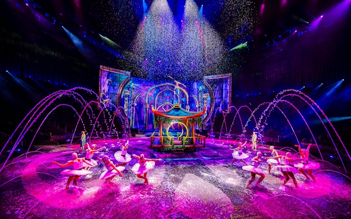 Performers in water dance at House of Dancing Water show, vibrant stage with fountains.