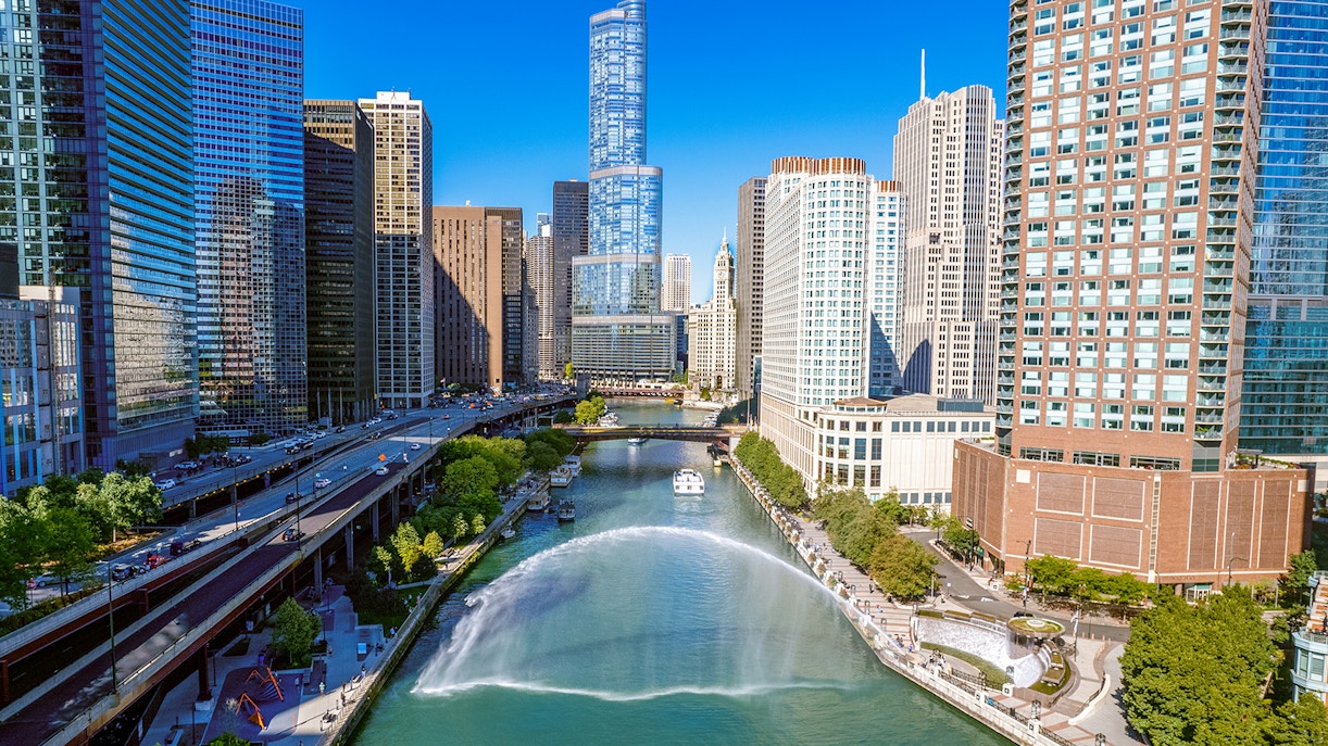 Centennial Fountain spraying water over the Chicago River with city skyline.