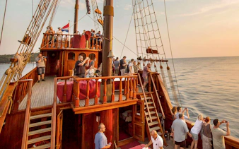Guests on Karaka Ship enjoying sunset views during a cruise.