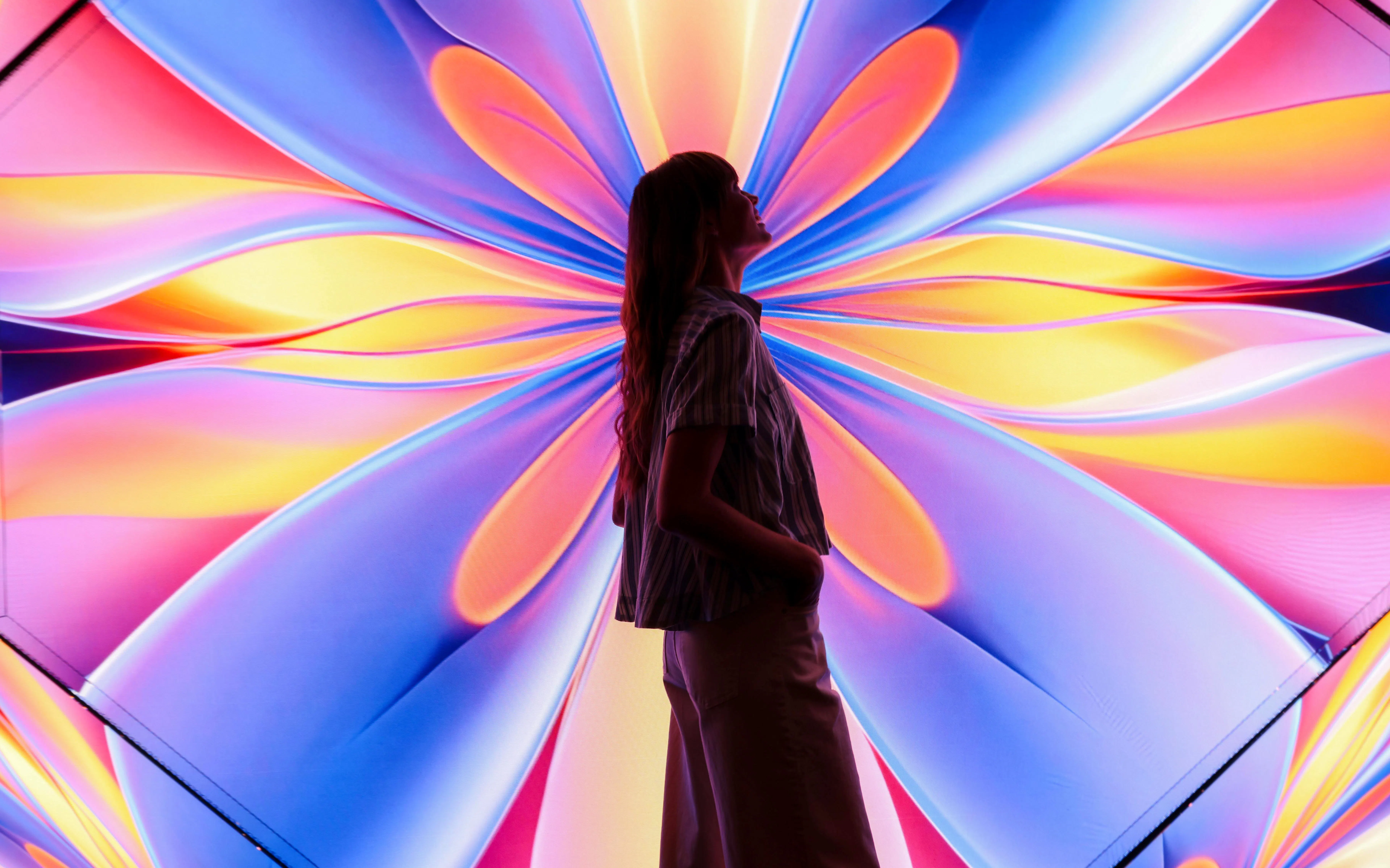 Silhouette of a person against colorful digital art at Edge Observatory, New York.