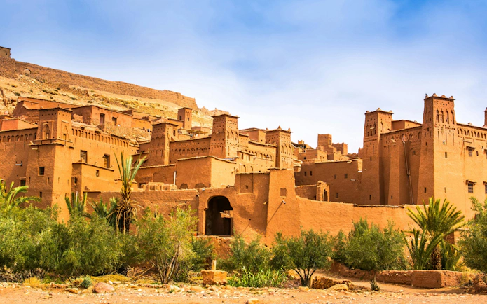 Ait Ben Haddou ancient clay architecture with palm trees in Morocco.