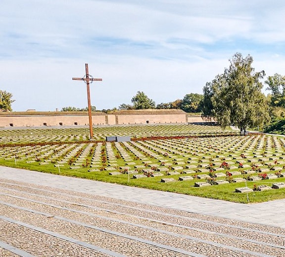 Terezin Concentration Camp cemetery with cross and rows of graves.
