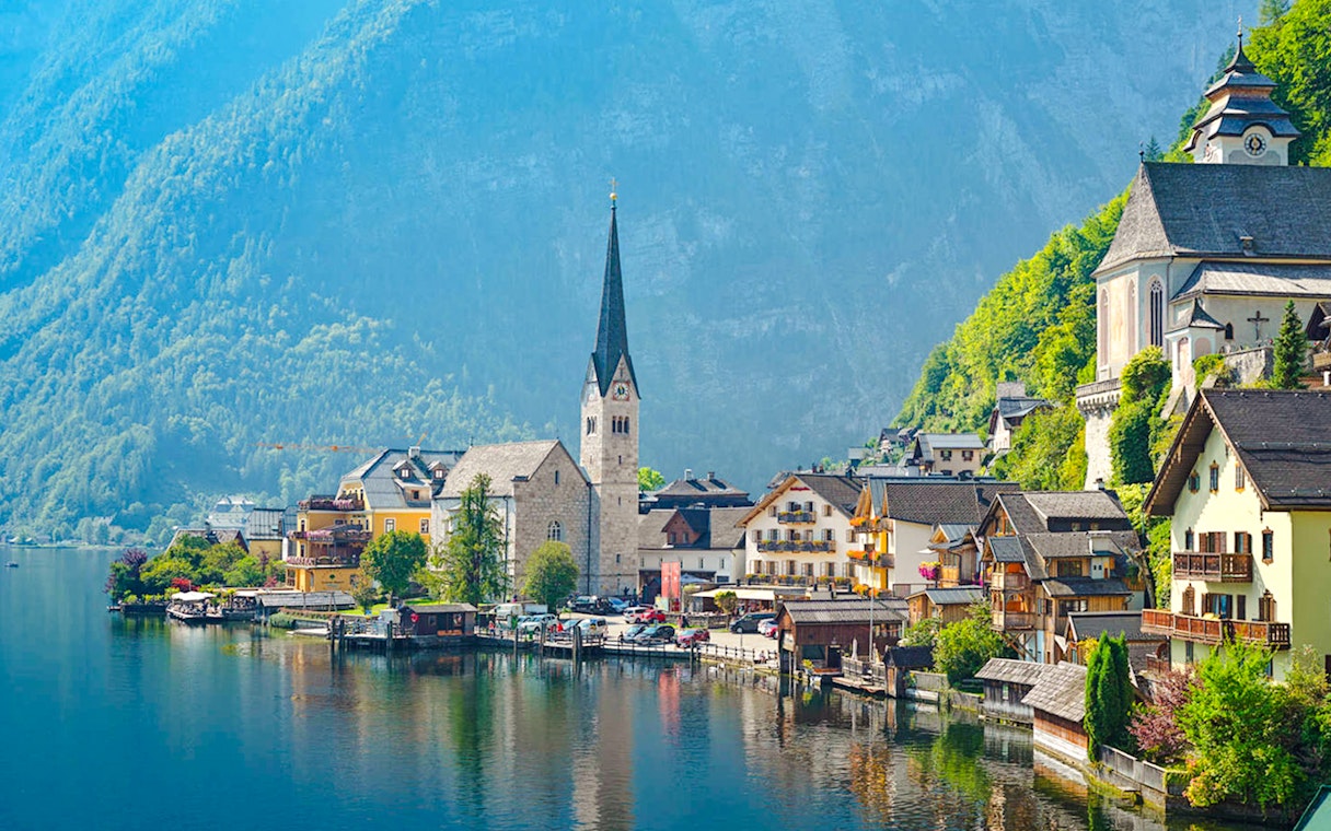 Village of Hallstatt, Austria with lakeside view and church spire against mountain backdrop.