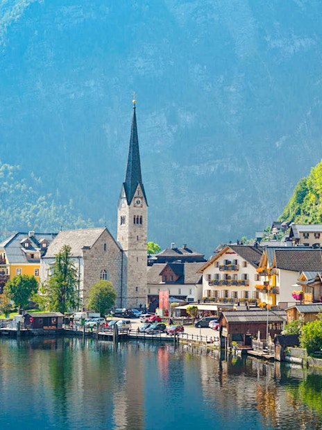 Village of Hallstatt, Austria with lakeside view and church spire against mountain backdrop.