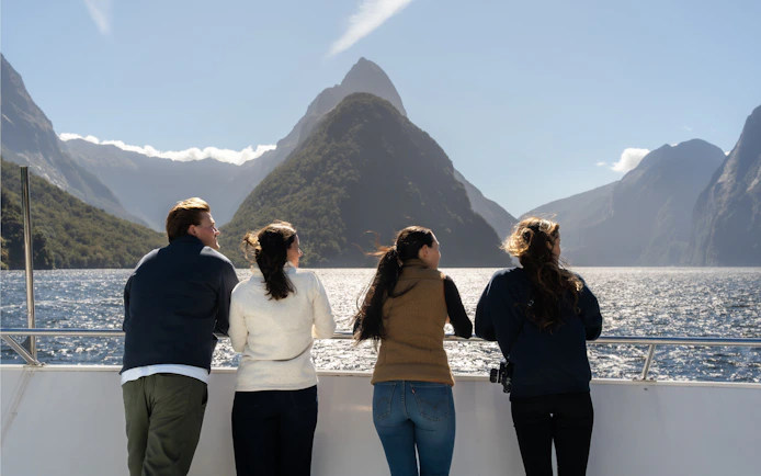Tourists enjoying a scenic view of Milford Sound from a cruise deck in New Zealand.