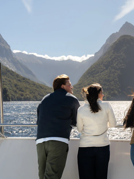 Tourists enjoying a scenic view of Milford Sound from a cruise deck in New Zealand.