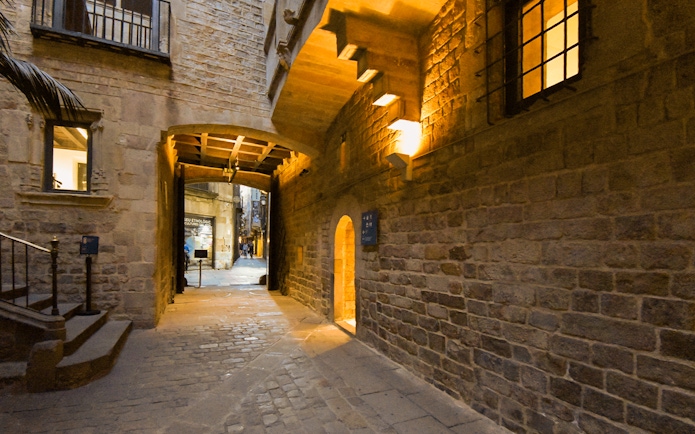Entrance to the Picasso Museum in Barcelona, featuring a stone archway and cobblestone path.