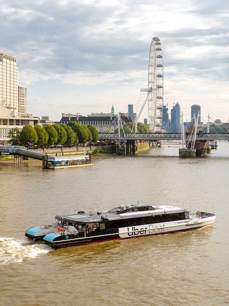 Uber Boat on Thames River with London Eye and Westminster in background.