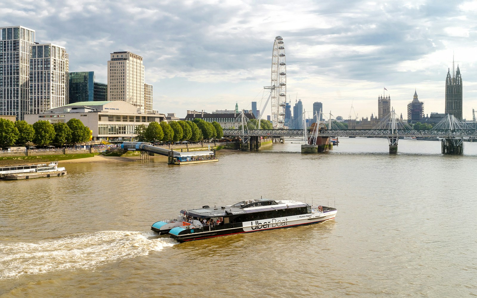 Thames River Uber Boat cruising past London Eye and Big Ben.