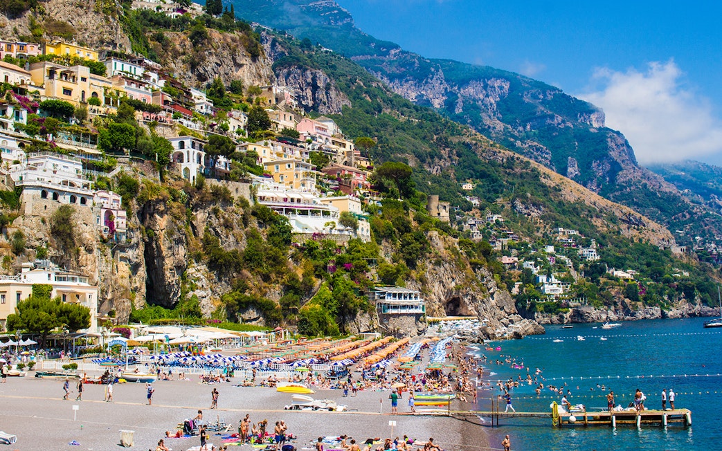 Positano's La Scogliera Beach with colorful umbrellas, part of Rome to Pompeii and Mount Vesuvius tour.