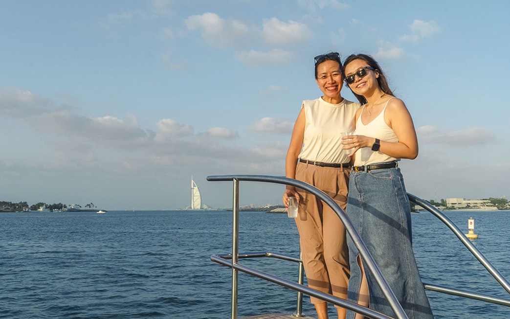 Two people enjoying a yacht cruise with a view of the Burj Al Arab in Dubai.