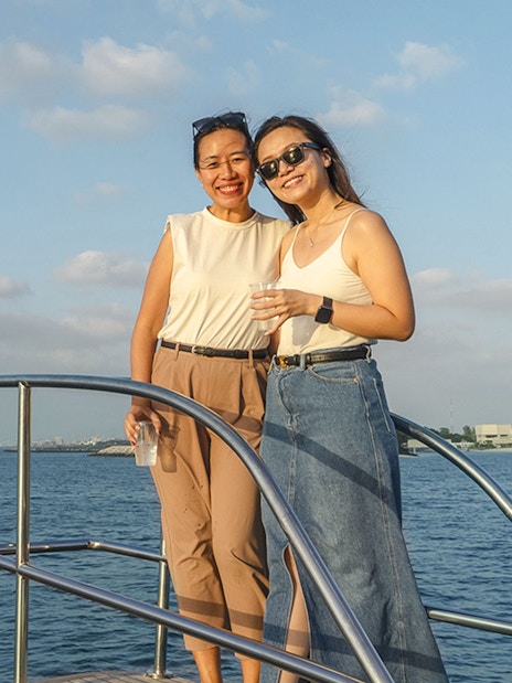 Two people enjoying a yacht cruise with a view of the Burj Al Arab in Dubai.