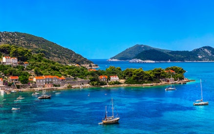 Sailboats near lush Elaphite Islands coast on Dubrovnik island-hopping cruise.