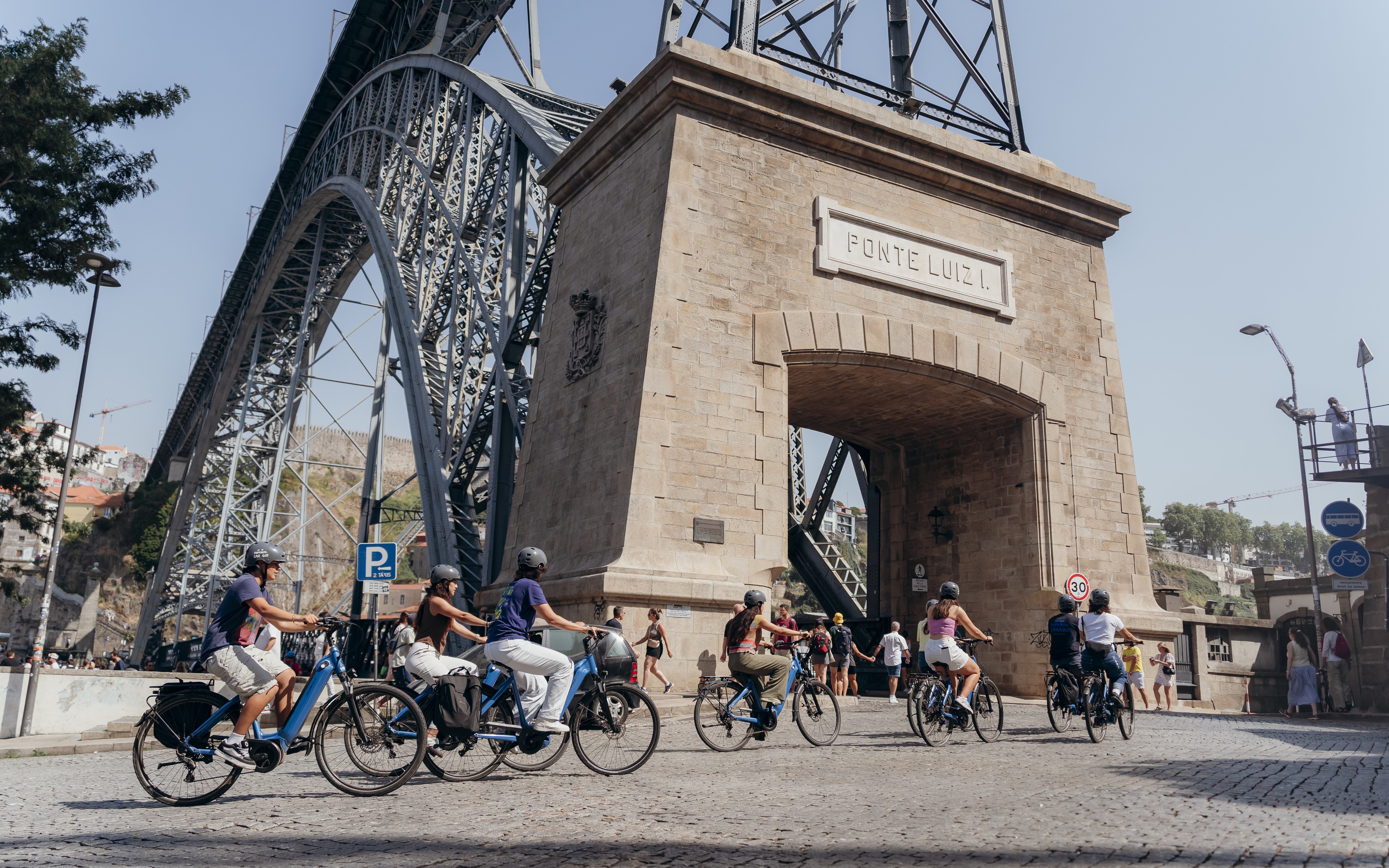 Tourists on electric bikes with guide near Dom Luís I Bridge in Porto.
