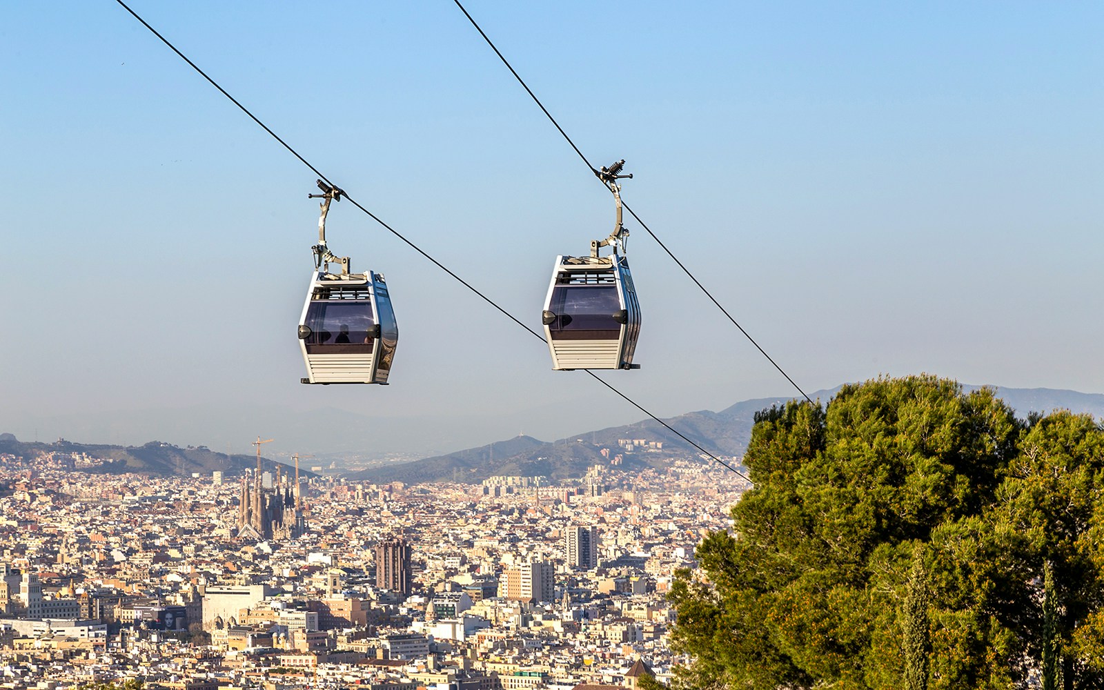 Cable car ascending Montjuic Hill with Sagrada Familia visible in the background, Barcelona.
