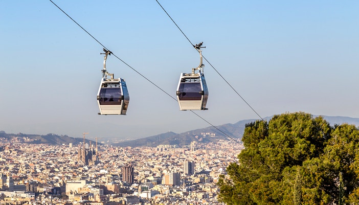 Cable car ascending Montjuic Hill with Sagrada Familia visible in the background, Barcelona.