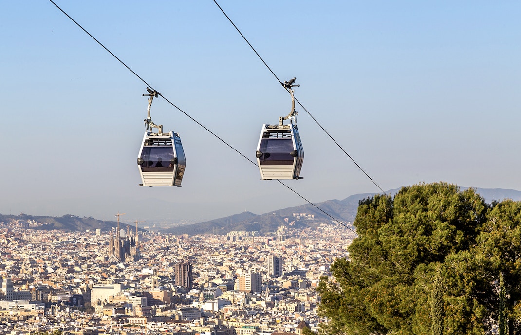Cable car ascending Montjuic Hill with Sagrada Familia visible in the background, Barcelona.