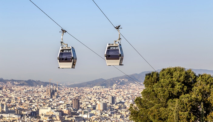 Cable car ascending Montjuic Hill with Sagrada Familia visible in the background, Barcelona.