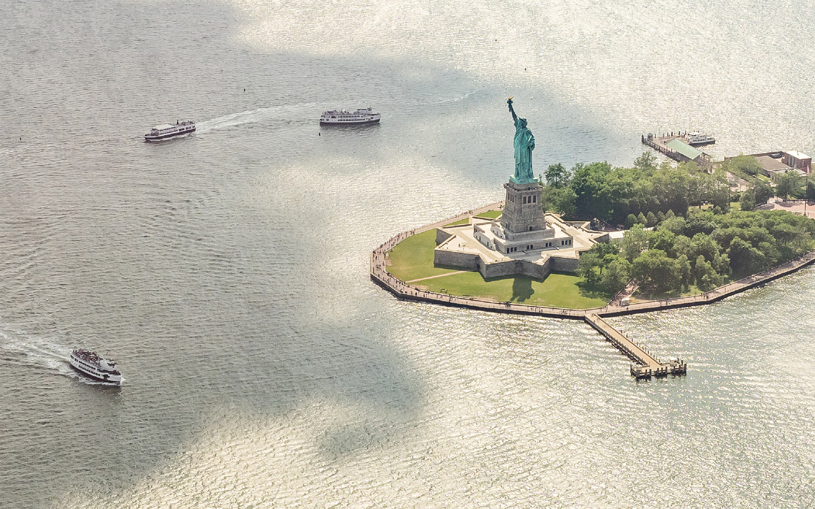 Statue of Liberty with ferries approaching, viewed from above, New York City.