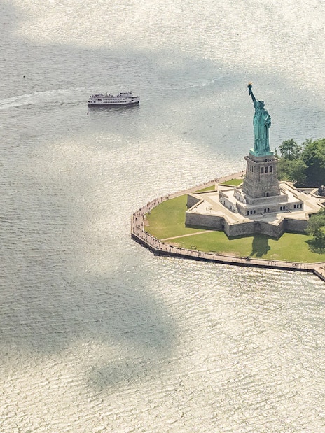 Statue of Liberty with ferries approaching, viewed from above, New York City.