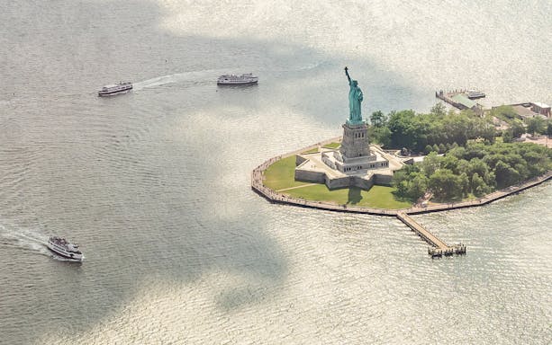 Statue of Liberty with ferries approaching, viewed from above, New York City.