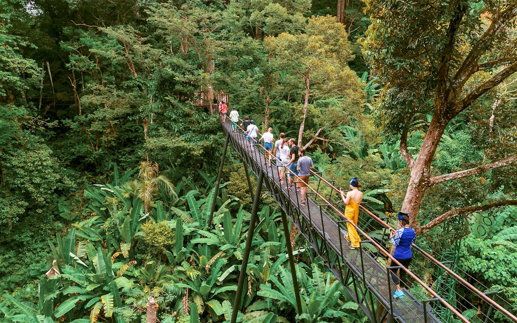 Visitors crossing a treetop platform at Hanuman World Phuket Zipline amidst lush greenery.
