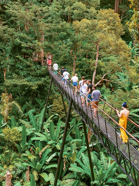Visitors crossing a treetop platform at Hanuman World Phuket Zipline amidst lush greenery.